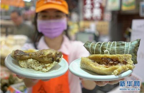 6月5日,台北南门市场“合兴”粽子摊的员工展示“鸡腿棒棒粽”(左)和肉粽。新华社记者 林善传 摄 6月5日,台北南门市场“合兴”粽子摊的员工展示“鸡腿棒棒粽”(左)和肉粽。新华社记者 林善传 摄